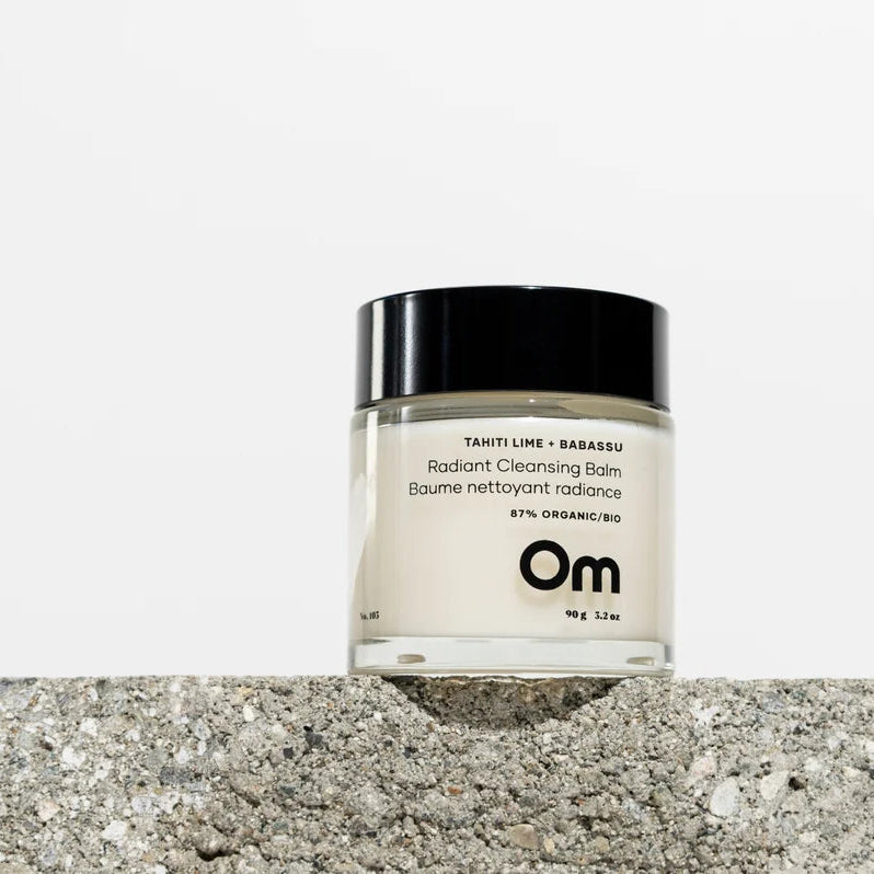 Jar of OM Organics product on a textured stone surface with a white background
